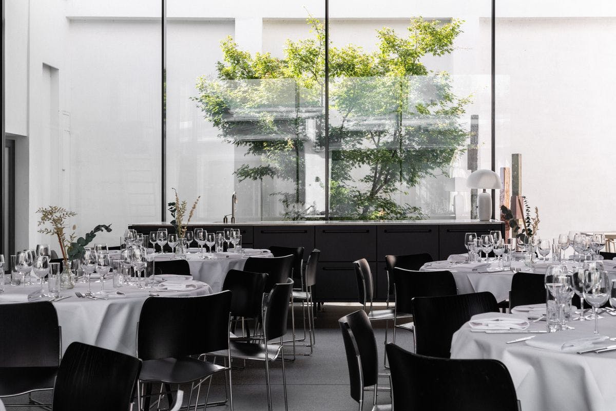 Elegant tables set up in the Garage at Mogens Dahl Concert Hall, ready for a corporate party with a focus on atmosphere and quality – ideal for themes, events, or dinners.