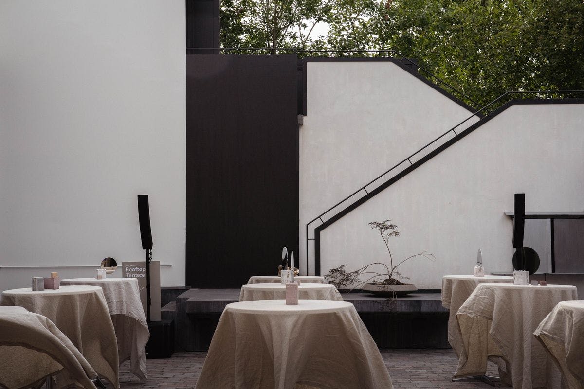 Tables elegantly set up in the cobblestone courtyard at Mogens Dahl Concert Hall, ready for an outdoor corporate party with a charming atmosphere and summer vibe.