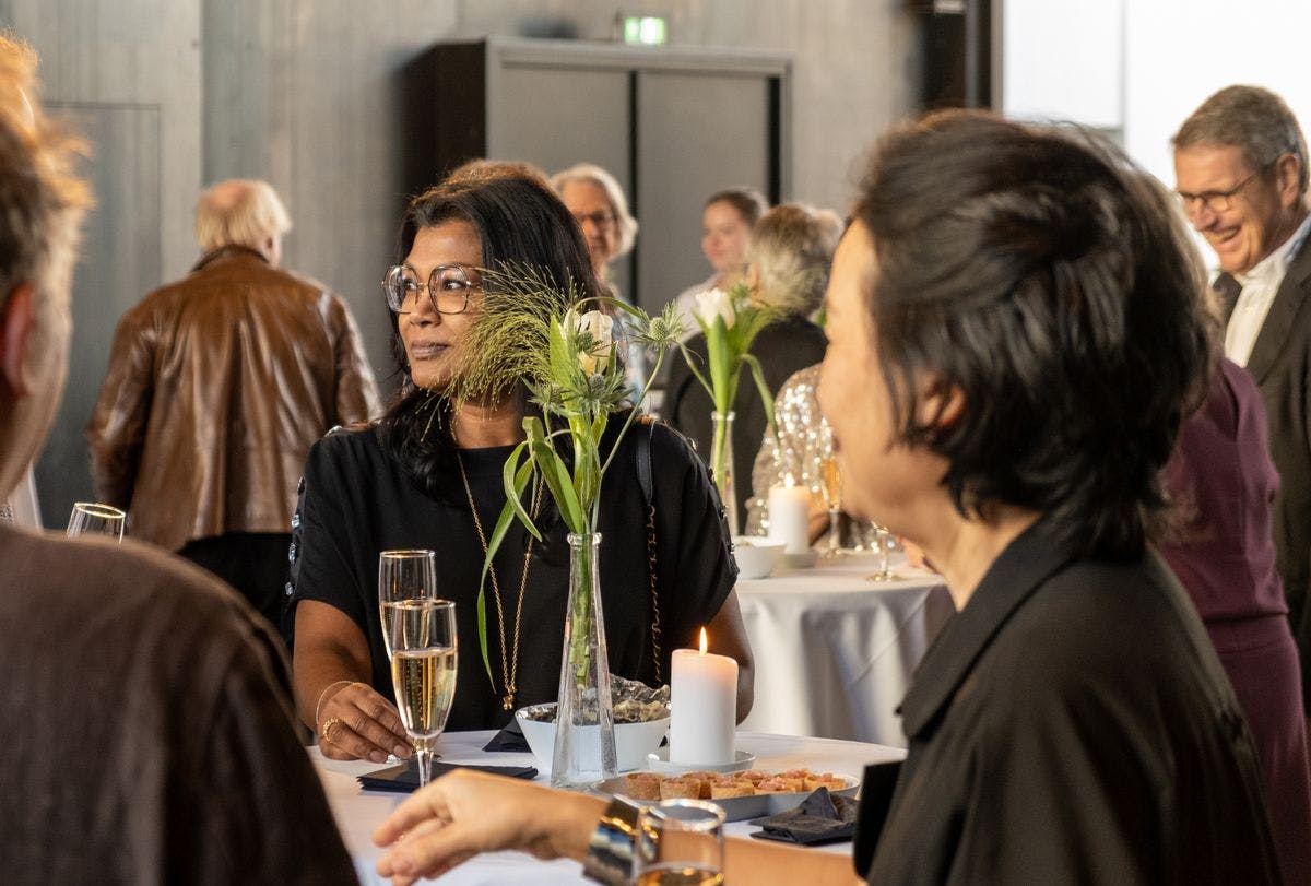 Guests enjoying an elegant dinner at a festive table during an event at Mogens Dahl Concert Hall, with a focus on a sophisticated and relaxed atmosphere.