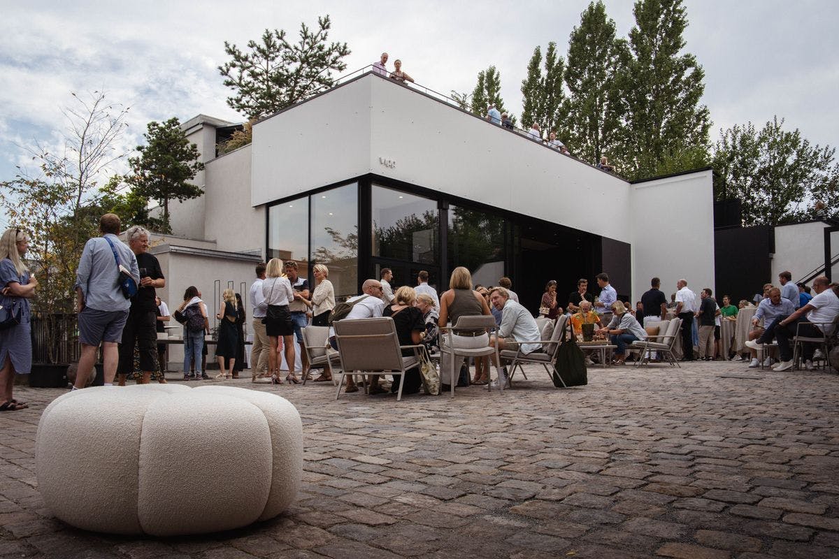 The courtyard filled with guests during an event at the Garage at Mogens Dahl Concert Hall. The image captures the busy and festive outdoor area where attendees are enjoying the event. The lively atmosphere in the courtyard highlights the Garage's ability to create an inviting and social experience for events.