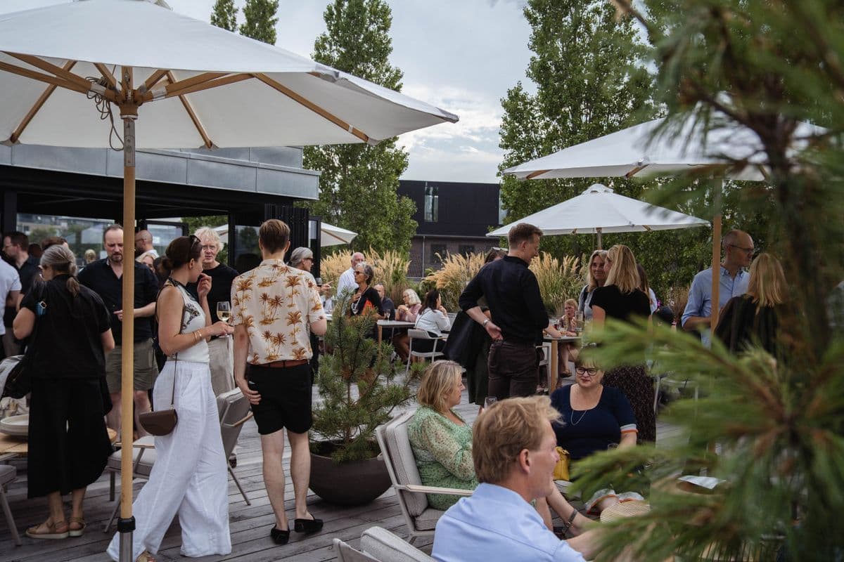 Gæster nyder et event på tagterrassen i Garagen på Mogens Dahl Koncertsal. Billedet viser en livlig scene med deltagere, der socialiserer og deltager i arrangementet på den stilfulde tagterrasse. Garagens tagterrasse tilbyder en unik udendørs oplevelse med en fantastisk udsigt, ideel til særlige begivenheder.