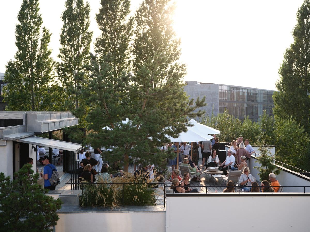 Billede af Garagens tagterrasse fyldt med gæster under et event i Mogens Dahl Koncertsal. Billedet viser den livlige atmosfære og den elegante udendørs opsætning, hvor gæster nyder arrangementet.